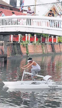  ?? PHOTOS BY JIRAPORN KUHAKAN ?? The prototype floating bicycle is a new attraction in the Bang Lamphu community. Tourists are encouraged to exercise on the ‘bikes’ and help clean the canal.