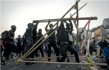  ?? AP ?? Protesters test a self-made catapult on the barricaded bridge into the Chinese University of Hong Kong.