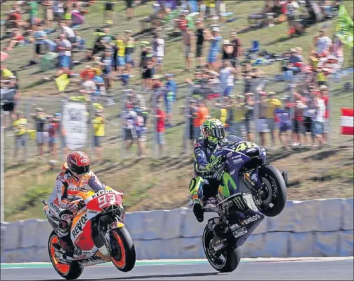  ??  ?? DUELO. Valentino Rossi hace un caballito delante de Márquez que se llevó la pole tras una cerrada lucha con el italiano y con Pedrosa.