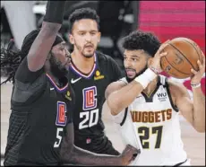  ?? Mark J. Terrill The Associated Press ?? Nuggets guard Jamal Murray tries to drive past Clippers forward Montrezl Harrell in the second half of Denver’s 110-101 win Saturday.