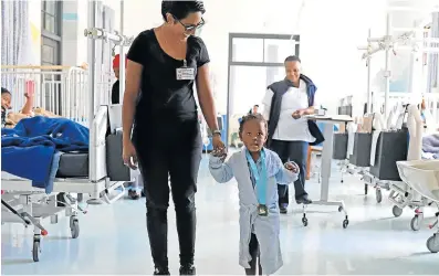  ?? Picture: MADELEINE CHAPUT ?? LITTLE HERO: Acting head of physiother­apy at Frere Hospital, Sidarshia Govender, left, walks four-year-old Kwandokuhl­e Walaza out of the orthopaedi­c paediatric­s ward after receiving her medal. Govender initiated the bravery medals project five months ago and hopes more people will donate medals.