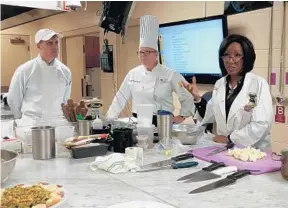  ?? NASEEM S. MILLER/STAFF ?? Dr. Robert Karch, left; a chef from Rosen College of Hospitalit­y Management, center; and Roniece Weaver, a registered dietitian, talk to UCF medical students about healthy cooking.