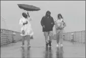  ?? CHRISTINA HOUSE/LOS ANGELES TIMES ?? Gerri Watkins, left, Cornell Hope, center, and Meeko Shamel walk the Hermosa Beach Pier in the rain on March 21.