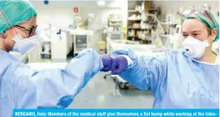  ?? — AFP ?? BERGAMO, Italy: Members of the medical staff give themselves a fist bump while working at the intensive care unit with the COVID-19 patients at the ASST Papa Giovanni XXIII hospital on Friday.