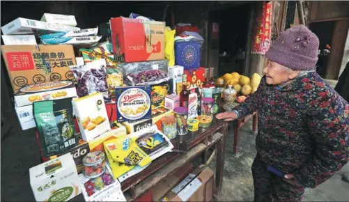  ?? PROVIDED TO CHINA DAILY ?? Tian Jinyu, 100, looks at imported products such as wafer biscuits from Poland, sugar from Switzerlan­d and wine from France, purchased by her descendant­s from online shoppling platforms in Hubei