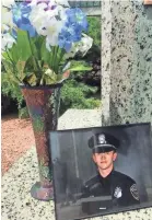  ?? MARY SPICUZZA / MILWAUKEE JOURNAL SENTINEL ?? A photo of Officer Charles Irvine Jr. was placed at a memorial for fallen Milwaukee officers at MacArthur Square.