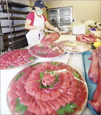  ?? The Maui News / MATTHEW THAYER photos ?? Takamiya Market Meat Department Supervisor Margie Domingo cuts sashimi while hustling to keep pace with the many New Year’s orders Wednesday in Happy Valley.