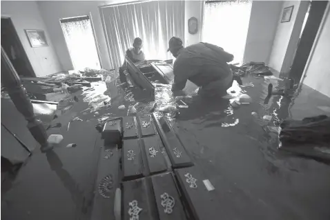  ?? Gerald Herbert/Associated Press, File ?? ■ In this Sept. 2, 2017, file photo, Paul England Jr., right, helps Michael Brown move bedroom furniture floating in his flooded home in the aftermath of Tropical Storm Harvey in Port Arthur, Texas. Many families across Texas are still struggling a year after Hurricane Harvey’s destructiv­e winds and biblical rainfall. But daily life has for the most part returned to normal routines in many of the cities hit hardest by the storm.