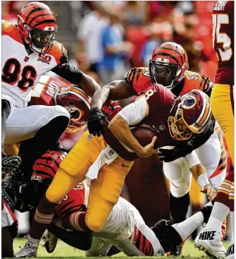  ?? PATRICK SMITH / GETTY IMAGES ?? Washington quarterbac­k Kirk Cousins gets sacked by defensive ends Chris Smith (94) and Wallace Gilberry (bottom) during the Bengals’ exhibition loss at FedExField.