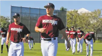  ?? David Santiago / Miami Herald ?? Miami Marlins catcher J.T. Realmuto (center) warms up with teammates as they wear Marjory Stoneman Douglas hats and T-shirts before the start of a spring training game.