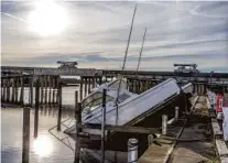  ?? MARK WALLHEISER/GETTY ?? Power company trucks drive over the Carrabelle River past boats damaged by Hurricane Michael at the Moorings of Carrabelle marina.