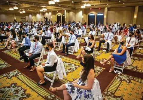  ?? Annie Mulligan / Contributo­r ?? Baylor College of Medicine students wait to receive their white coats in a ceremony Aug. 13 at the Bayou City Event Center. An earlier event for new medical students, before CDC guidance changed, resulted in breakthrou­gh COVID cases.