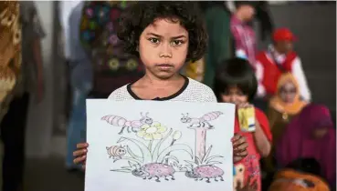  ?? — AFP ?? A beautiful world: Nine-year-old Suminawati showing her drawing at a relief centre in Kalianda in Lampung province.