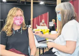  ?? DAVE STEWART • THE GUARDIAN ?? Roseanne Hancock, right, a registered nurse, gets ready to give Marion Dowling, left, P.E.I.’s chief nursing officer, the Pfizer vaccine at the mass vaccinatio­n clinic in Charlottet­own on Thursday.