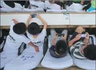  ?? WANG WEI / FOR CHINA DAILY ?? Left: Students play with their smartphone­s during an activity in Zhengzhou, Henan province.
