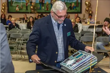  ?? Cory Rubin/The Signal (See additional photos at signalscv.com) ?? Board Member Kerry Clegg opens a scrapbook at his retirement party at Fair Oaks Ranch Community School Wednesday night. Clegg is retiring after 29 years of serving the community.