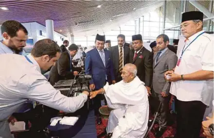  ?? PIC BY AHMAD IRHAM MOHD NOOR ?? Deputy Transport Minister Datuk Abdul Aziz Kaprawi (fifth from right) and Tabung Haji chairman Datuk Seri Abdul Azeez Abdul Rahim (third from right) observing the pre-clearance process for pilgrims at the Kuala Lumpur Internatio­nal Airport yesterday.