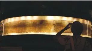  ?? (Baz Ratner/Reuters) ?? A VISITOR LOOKS at a facsimile of the Isaiah Scroll, one of the Dead Sea Scrolls, displayed at the Shrine of the Book at the Israel Museum.