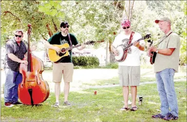  ??  ?? Kevin Watkins, Jason Reddecliff, Owen McClung and Tim McClung with Porchlight Symphony of Fayettevil­le presented an afternoon concert Saturday at Mock Park in Prairie Grove. About 40 people enjoyed the shade as they listened to bluegrass music. The concert was part of 2nd Saturday Trades Day.