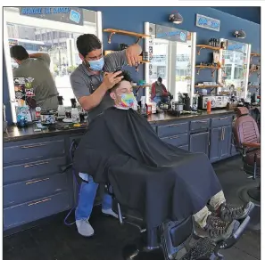  ?? (Arkansas Democrat-Gazette/Thomas Metthe) ?? Barber Alain “Pachi” Ravelo cuts the hair of Landon Friend on Monday at Handle Barbershop in downtown Little Rock. Manager Cody Mayes, commenting on the shop’s mask policy after the state mandate expires, said that “I’m going to leave it up to the client’s discretion.”