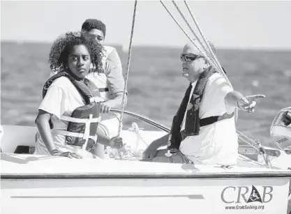  ?? PAUL W. GILLESPIE/BALTIMORE SUN MEDIA GROUP PHOTOS ?? Nabila Hinton, left, 14, of Laurel, a guest of the Anne Arundel County police, listens to volunteer skipper Art Savage, right, while racing. Chesapeake Region Accessible Boating hosted a sailing camp for police and disadvanta­ged youths at Sandy Point...