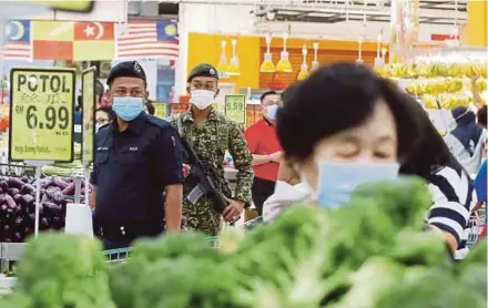  ?? PIC BY HAIRUL ANUAR RAHIM ?? Armed forces and police personnel on patrol to ensure the public comply with Covid-19 standard operating procedures at a supermarke­t in Petaling Jaya yesterday.