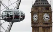  ?? FRANK AUGSTEIN — THE ASSOCIATED PRESS FILE ?? In this file photo, visitors enjoy the London Eye ride beside The Elizabeth Tower housing the Big Ben bell on a cloudy day in London.