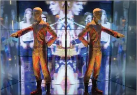  ?? ?? A reflection of the costume that David Bowie wore as Ziggy Stardust on tour and during a performanc­e of “Starman” on British pop music show “Top of The Pops” is shown as part of a retrospect­ive David Bowie exhibition, entitled “David Bowie Is” at the V&A Museum in west London in 2013.
