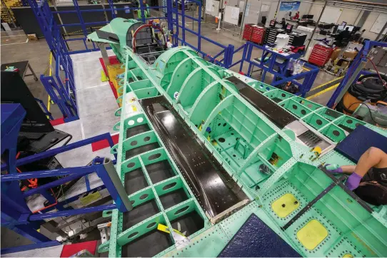  ??  ?? ABOVE At Lockheed Martin’s Skunk Works factory in Palmdale, California, an engineer works on the fuselage section of the X-59. The black rectangula­r panels are air intakes for the plane’s environmen­tal control system (ECS), and the silver grate is the ECS exhaust. These features are placed on the top of the craft to reshape the shock wave pattern