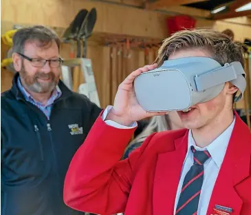  ?? MYTCHALL BRANSGROVE/ STUFF ?? Geraldine High School student Robert Furrer, 16, tries out a VR headset teaching about farm safety while WorkSafe engagement lead Al McCone looks on.