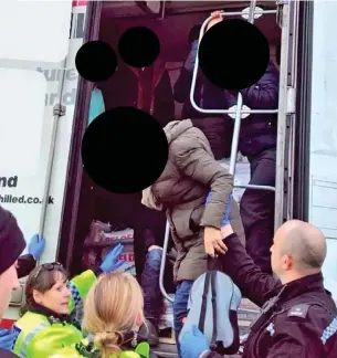  ??  ?? Freed: Police help some of the 11 migrants out of the back of the lorry. Their faces have been obscured to protect their identities