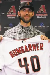  ?? Matt York / Associated Press ?? Madison Bumgarner, holding his Diamondbac­ks jersey Tuesday, is the 2014 World Series MVP, a threetime World Series champion and a fourtime AllStar. He had 119 wins and a 3.13 career ERA with the Giants.