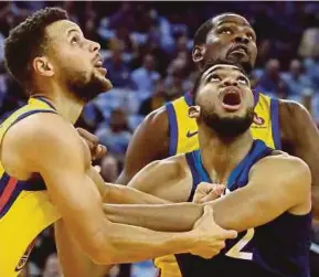  ?? AFP PIC ?? Warriors’ Stephen Curry (left) and Kevin Durant (back) in action against Timberwolv­es Karl-Anthony Towns in Oakland on Thursday.