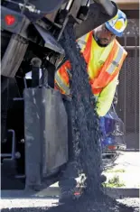  ??  ?? David Randolph pours asphalt as part of the blitz of 12-hour days for three weeks, hoping to cut into Oakland’s $500 million road maintenanc­e backlog.