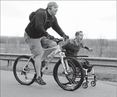  ??  ?? Wounded veterans urged to get out in public: Bryan Anderson lets go of cyclist John Pisano’s bike as they race through a parking lot at the Susquehann­a River Dike in Wyoming, Pa.