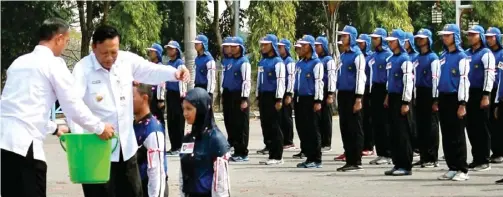  ?? CHUSNUL CAHYADI/JAWA POS ?? LATIHAN AWAL: Bupati Sambari Halim mengguyurk­an air kembang kepada calon anggota paskibra di halaman kantor Pemkab Gresik kemarin.