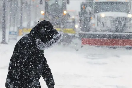  ?? CLIFFORD SKARSTEDT EXAMINER ?? A pedestrian is bundled up as city plows clear the snow accumulati­on on Tuesday in downtown Peterborou­gh.