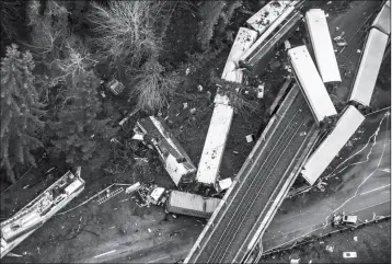  ?? BETTINA HANSEN/THE SEATTLE TIMES VIA AP ?? CARS FROM AN AMTRAK TRAIN THAT DERAILED ABOVE LIE SPILLED onto Interstate 5 on Monday in DuPont, Wash. The Amtrak train making the first-ever run along a faster new route hurtled off the overpass Monday near Tacoma and spilled some of its cars onto the...