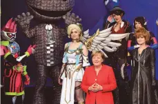  ?? FOTO: AFP ?? Angela Merkel zwischen Figuren aus Computersp­ielen. Zum ersten Mal eröffnete die Kanzlerin die weltweit größte Games-Messe.