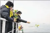  ?? SOUTH KOREAN MINISTRY OF OCEANS AND FISHERIES VIA AP ?? During a memorial service in waters off Jindo, South Korea, on Tuesday, relatives of missing passengers from the 2014 Sewol ferry disaster hurl flowers into the sea.