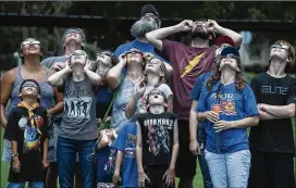  ?? ANDY SHARP / FOR AMERICAN-STATESMAN ?? Members of Cub Scout Pack 182 in Elgin and their family members watch the eclipse Monday outside the Taylor Public Library. The Taylor library gave out free eclipse glasses — as well as Moon Pies — for the solar eclipse, which at its local peak was at...