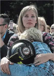 ?? FRED CHARTRAND THE CANADIAN PRESS ?? Elizabeth Hargrave, widow of firefighte­r James Hargrave of Cypress County Walsh Fire Station, Alberta, holds her son Hudson, 6, after they were presented with her husband’s ceremonial helmet during the Firefighte­rs’ National Memorial Day ceremony in Ottawa on Sunday.