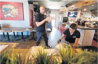  ?? STEPHEN M. DOWELL/ORLANDO SENTINEL PHOTOS ?? Thomas Ward, middle, works on several takeout orders at his restaurant, Pig Floyd’s in Orlando, on April 3.