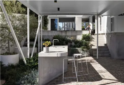  ??  ?? CENTRAL COURTYARD Above and above right The family relaxes in the home’s central courtyard. Casuarina glauca ‘Cousin It’ and Dichondra repens ‘Silver Falls’ cascade over the planters, which are filled with a mix of succulents. Tidal outdoor setting, Tait. Crazy paving in Porphyry and Endicott, Eco Outdoor. OUTDOOR
KITCHEN Right Equipped with a concrete bench and Brodware mixer, the outdoor kitchen is in one of the home’s undercroft­s. Hay ‘Hee’ stools, Cult. Planters, Quatro Design. Pavers, Eco Outdoor.