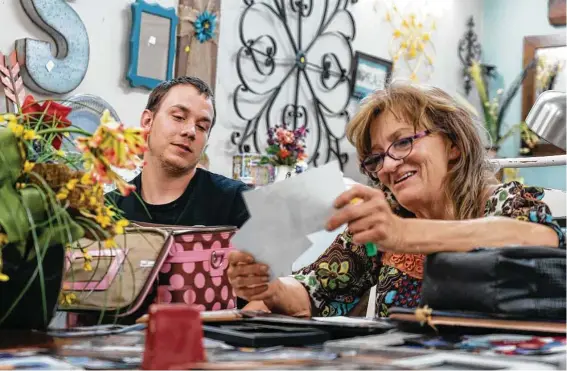  ?? Mark Mulligan / Staff photograph­er ?? Elizabeth Waller and her youngest son, Colton White, are able to smile as they look through family photograph­s at Elizabeth’s resale shop in Flint.