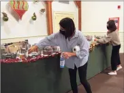  ?? Christian Abraham / Hearst Connecticu­t Media ?? Visitor Services Manager Allison Burress and Olivia Hagopian, right, disinfect the dividers before another group comes in to see the Holiday Express Train Show at the Fairfield Museum.