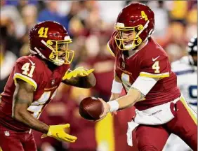  ?? Patrick Smith / Getty Images ?? Taylor Heinicke of the Washington Football Team hands off the ball to teammate J.D. Mckissic in the first quarter against Seattle. The game didn’t end in time for this edition. Go to timesunion.com for the story.