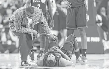  ?? Gabrielle Lurie / San Francisco Chronicle ?? James Harden is tended to after suffering a mishap in the Rockets’ loss to the Warriors on Friday night at Oracle Arena in Oakland, Calif. Harden has been hampered by a bothersome injury to his left wrist.