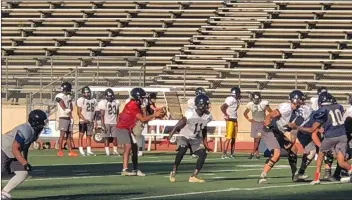  ?? Dan Lovi/The Signal ?? (Above) Canyons’ quarterbac­k Andrew Brito takes a snap in practice on Wednesday. (Below) Canyons’ Brito throws a pass to wide receiver Leroy Deshazor during practice on Wednesday at Cougar stadium.