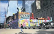  ?? MARK LENNIHAN—ASSOCIATED PRESS ?? A woman walks by the colorful murals that surround the foundation for 2World Trade Center, Wednesday, Sept. 8, 2021in New York. Planned as the second tallest skyscraper at the site, 2 World Trade Center, might someday reach 80stories. Developer Larry Silverstei­n has said he wants to sign an anchor tenant for the tower before starting constructi­on.